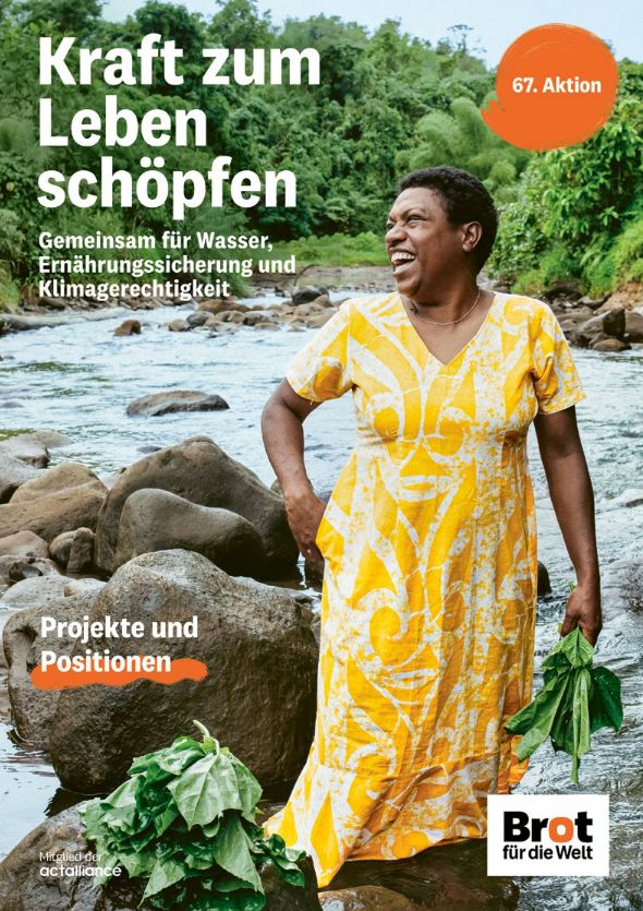 Eine afrikanische Frau in gelbem Kleid steht lachend in einem Fluss