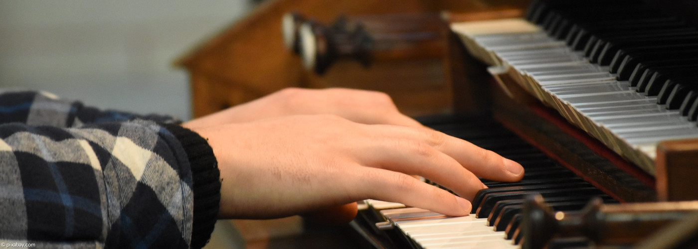 Die Hand eines Jungen, die über Orgeltasten schwebt