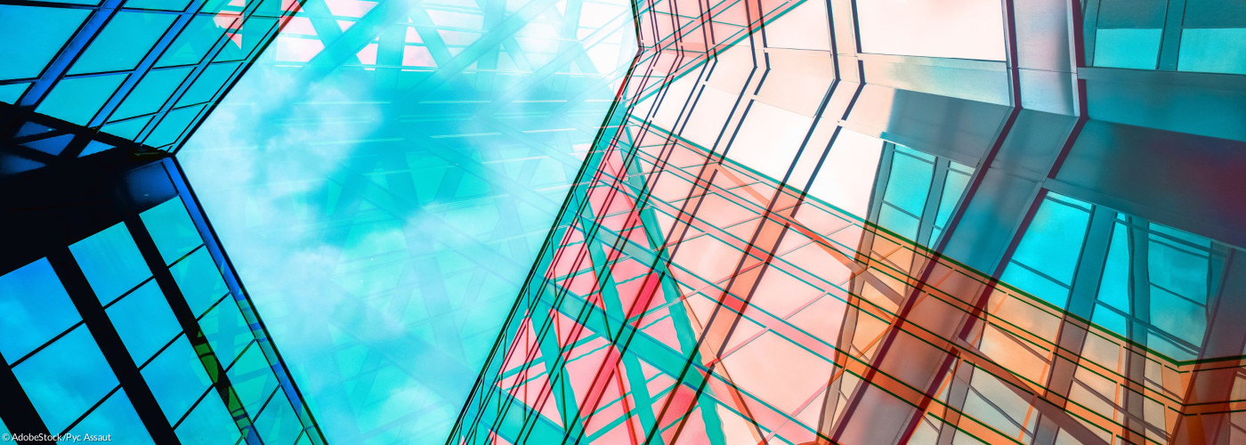 Eine Architektur aus Glas und Stahl spiegelt den blauen Himmel darüber.