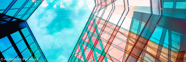 Eine Architektur aus Glas und Stahl spiegelt den blauen Himmel darüber.